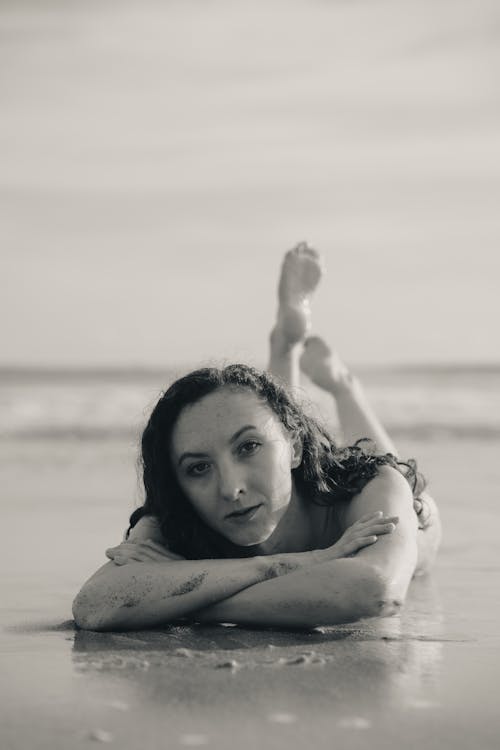 Grayscale Photo of a Woman Lying Down on Beach