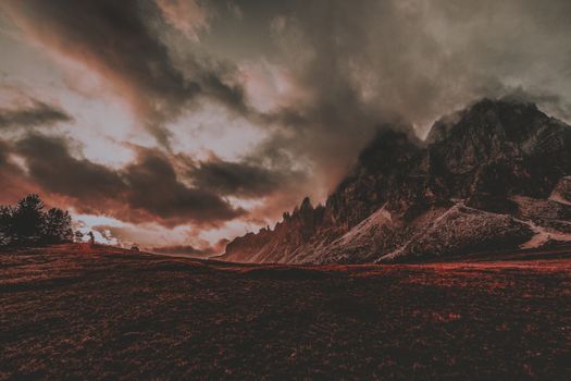 Majestic mountains under dramatic cloudy sky during dusk in the Dolomites, capturing nature's raw beauty.
