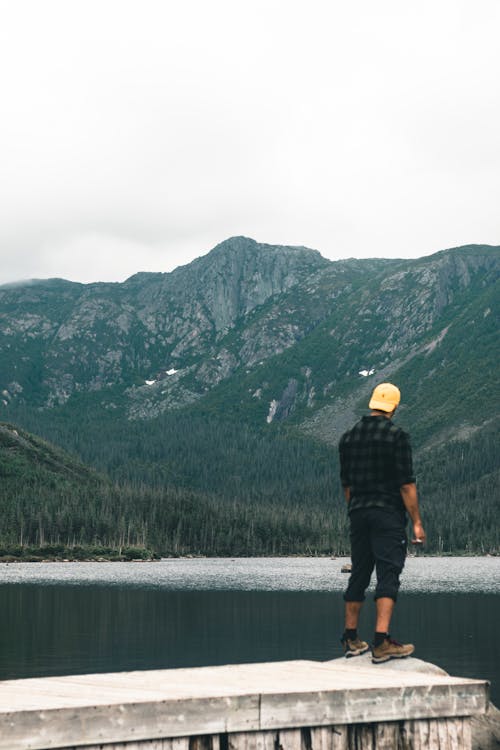 Hiker Standing by Lake, and Looking at Mountains