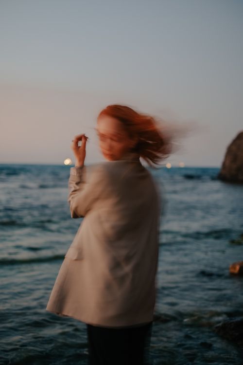 Free Abstract image of a woman by the seaside at dusk, capturing motion and serenity. Stock Photo