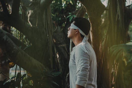 一名男子蒙住双眼，在宁静的森林中站立，感受自然