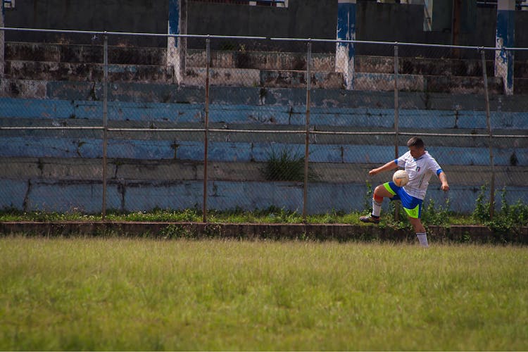 Man Playing Football On Green Grass Field