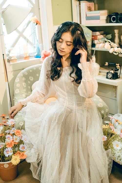 Woman in Tulle Dress Sitting on Armchair Surrounded by Flowers