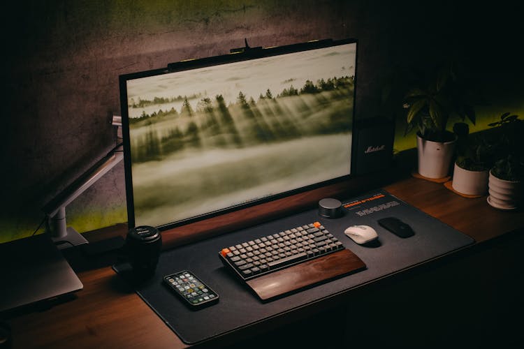 A Computer Setup On A Wooden Desk