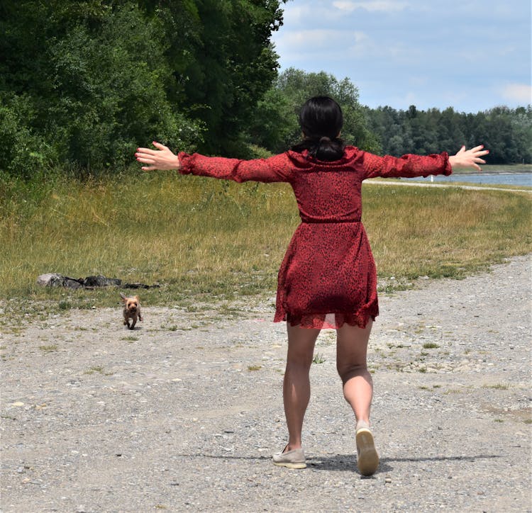 A Dog Running Towards The Woman In A Red Dress