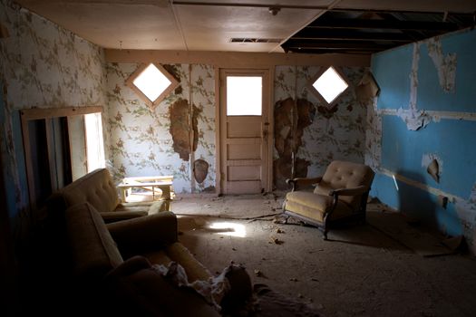 An abandoned room in Arizona with peeling wallpaper and vintage chairs, creating a mysterious and nostalgic atmosphere.