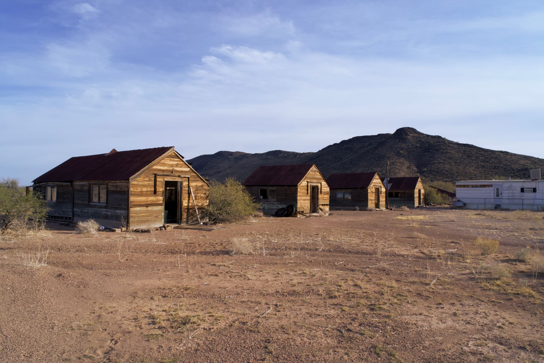Historic wooden structures in an abandoned Arizona ghost town set against a desert backdrop.