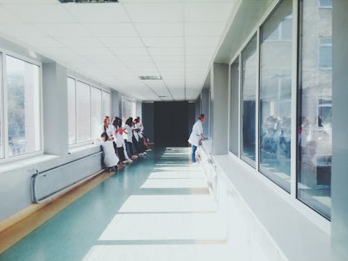 Free Woman in White Shirt Standing Near Glass Window Inside Room Stock Photo