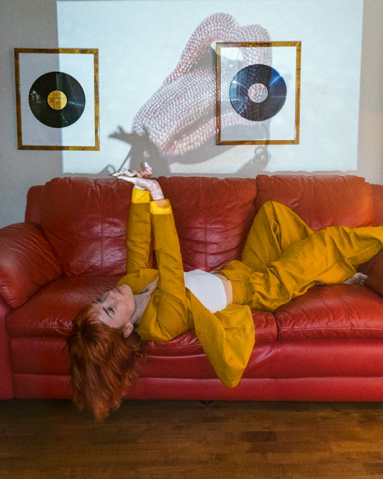 A Woman In Yellow Suit Lying On Red Couch