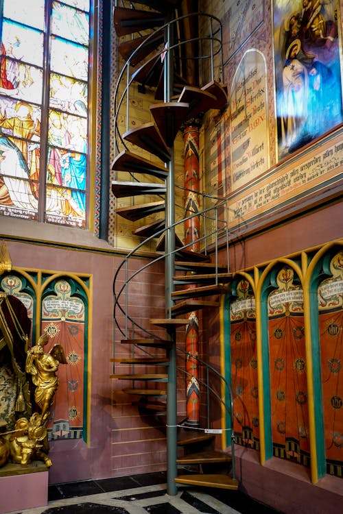 A Wooden Spiral Staircase Near Stained Glass Window