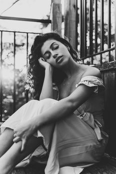 Black and white portrait of a woman sitting outdoors with eyes closed.