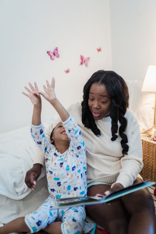 Free A mother and daughter enjoying bedtime reading together in a cozy bedroom. Stock Photo