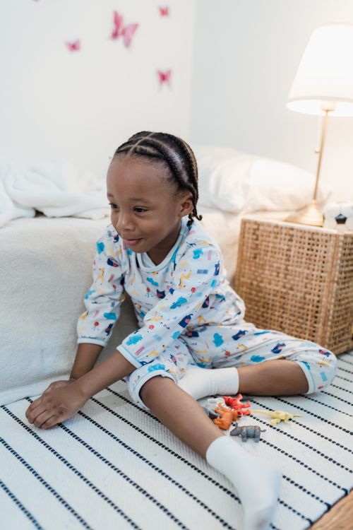 Free A cheerful child in pajamas playing with toys in a cozy bedroom setting. Stock Photo