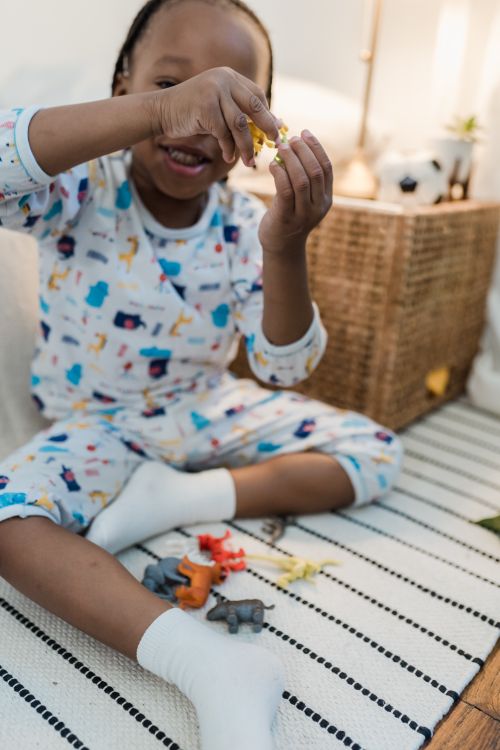 Free Child enjoying playtime with toy animals in a comfortable indoor setting. Stock Photo