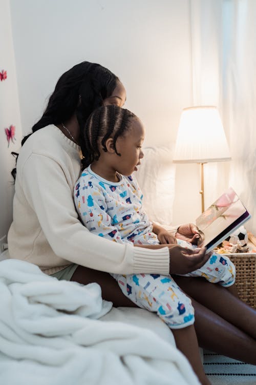 Woman Reading Book with Daughter in Bedroom