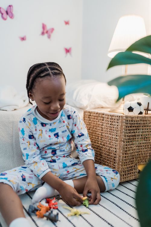 Free A happy child in pajamas playing with toys in a cozy bedroom setting. Stock Photo