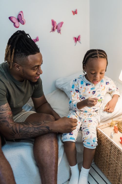 Free A father enjoys quality time with his daughter before bedtime in a cozy bedroom setting. Stock Photo