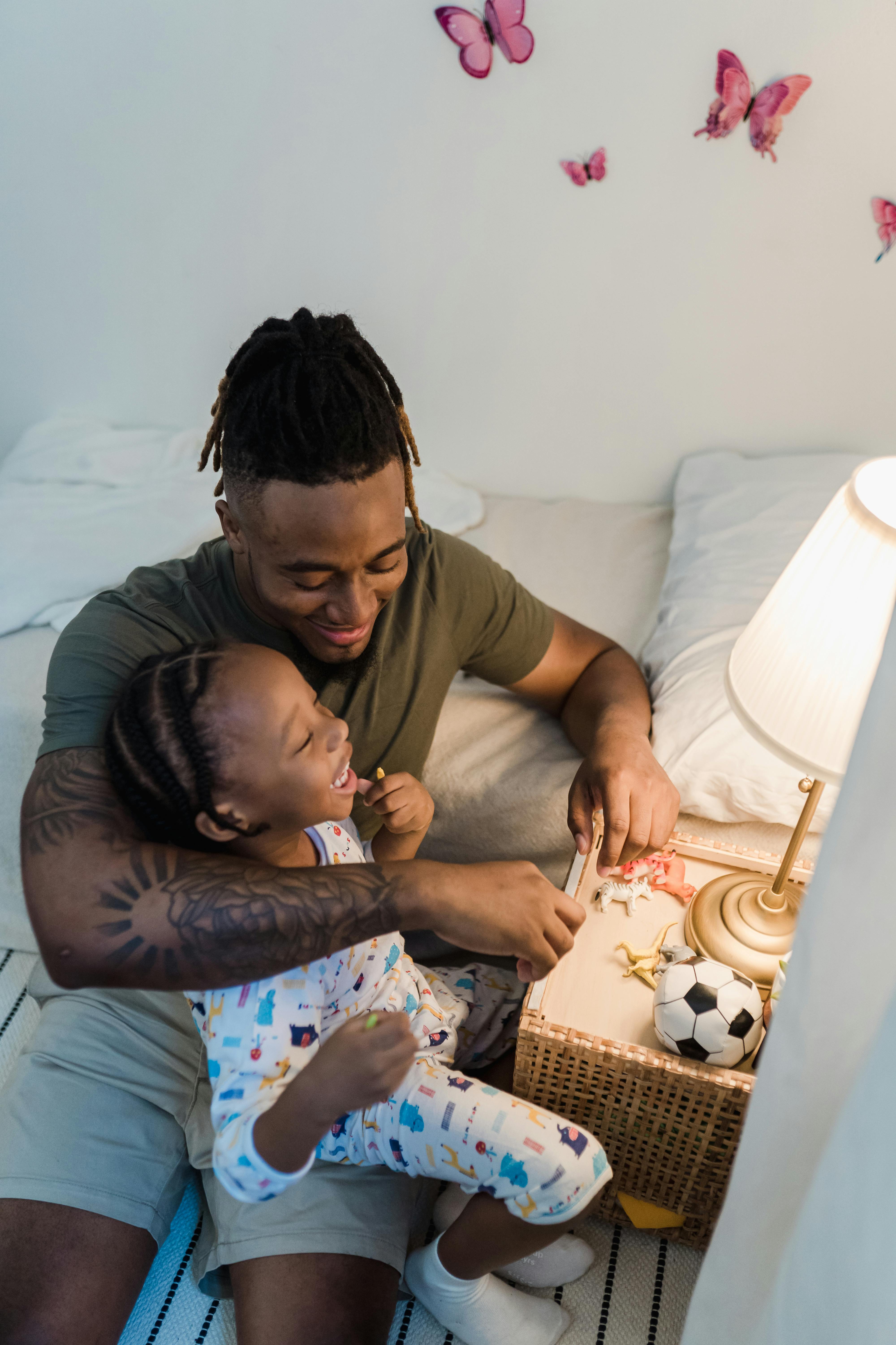 Father and daughter sharing a joyful moment in a beautifully decorated bedroom under warm lighting.
