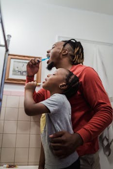 A father and daughter sharing a morning routine of brushing teeth at home.