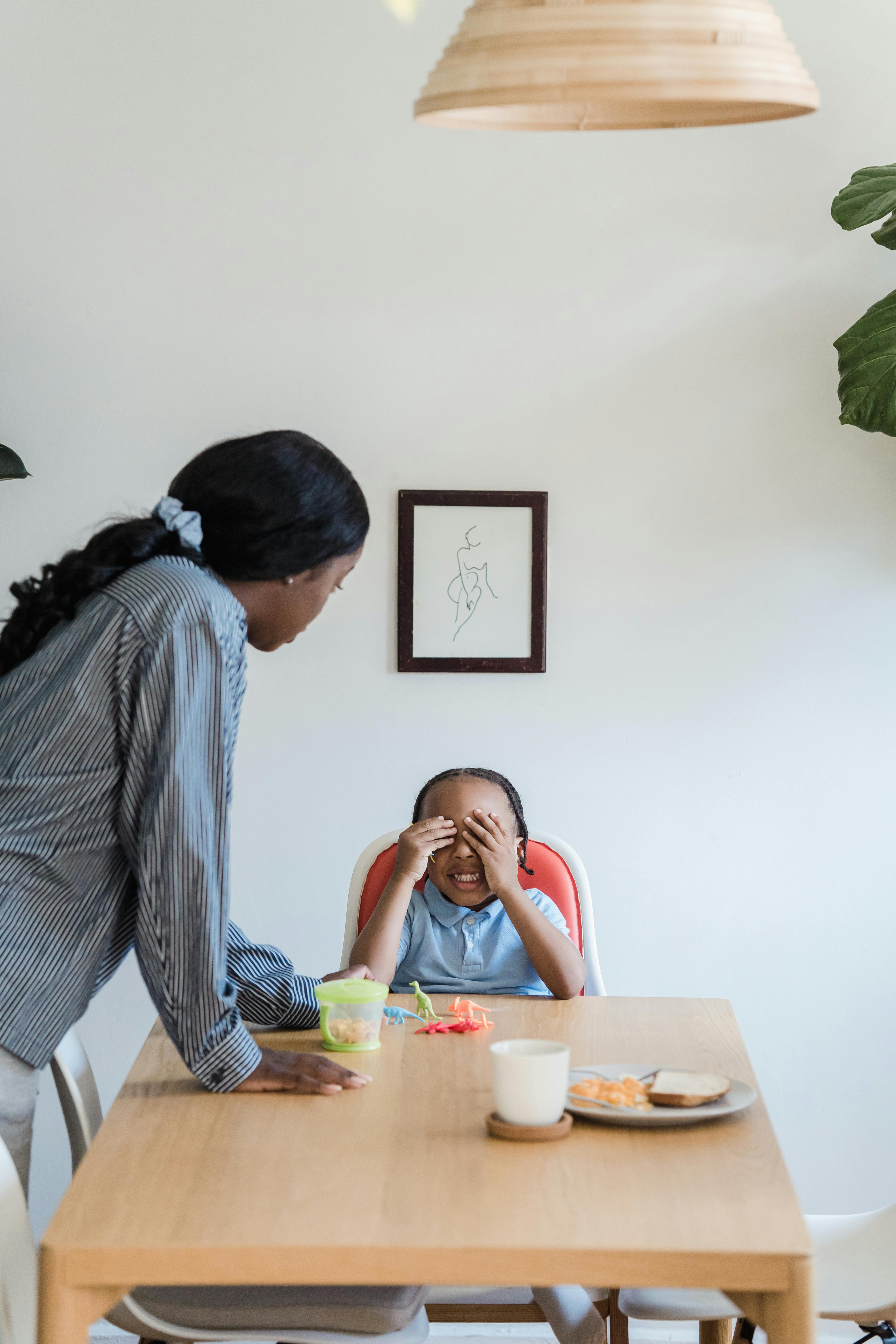 mother talking to her little son while he sits behind a table at lunch