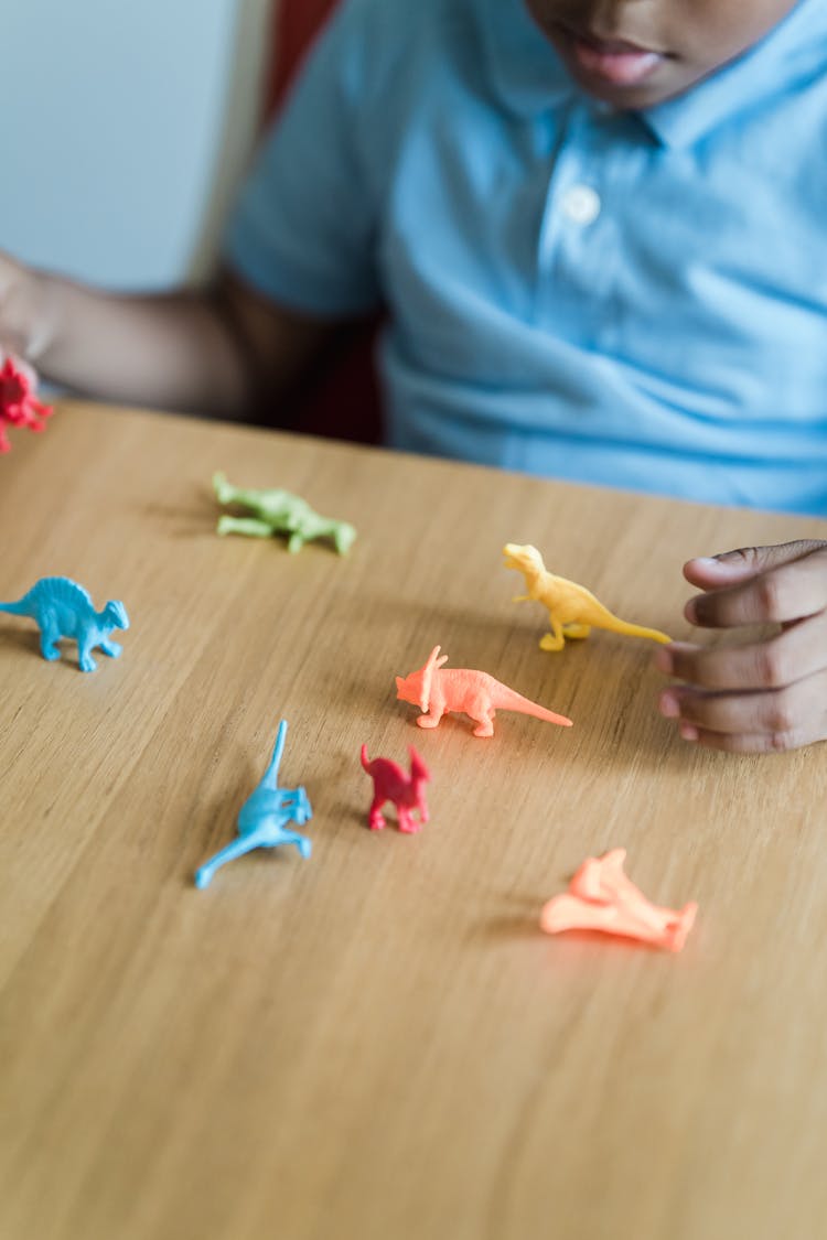 Close-up Of A Little Boy Playing With Plastic Dinosaurs 