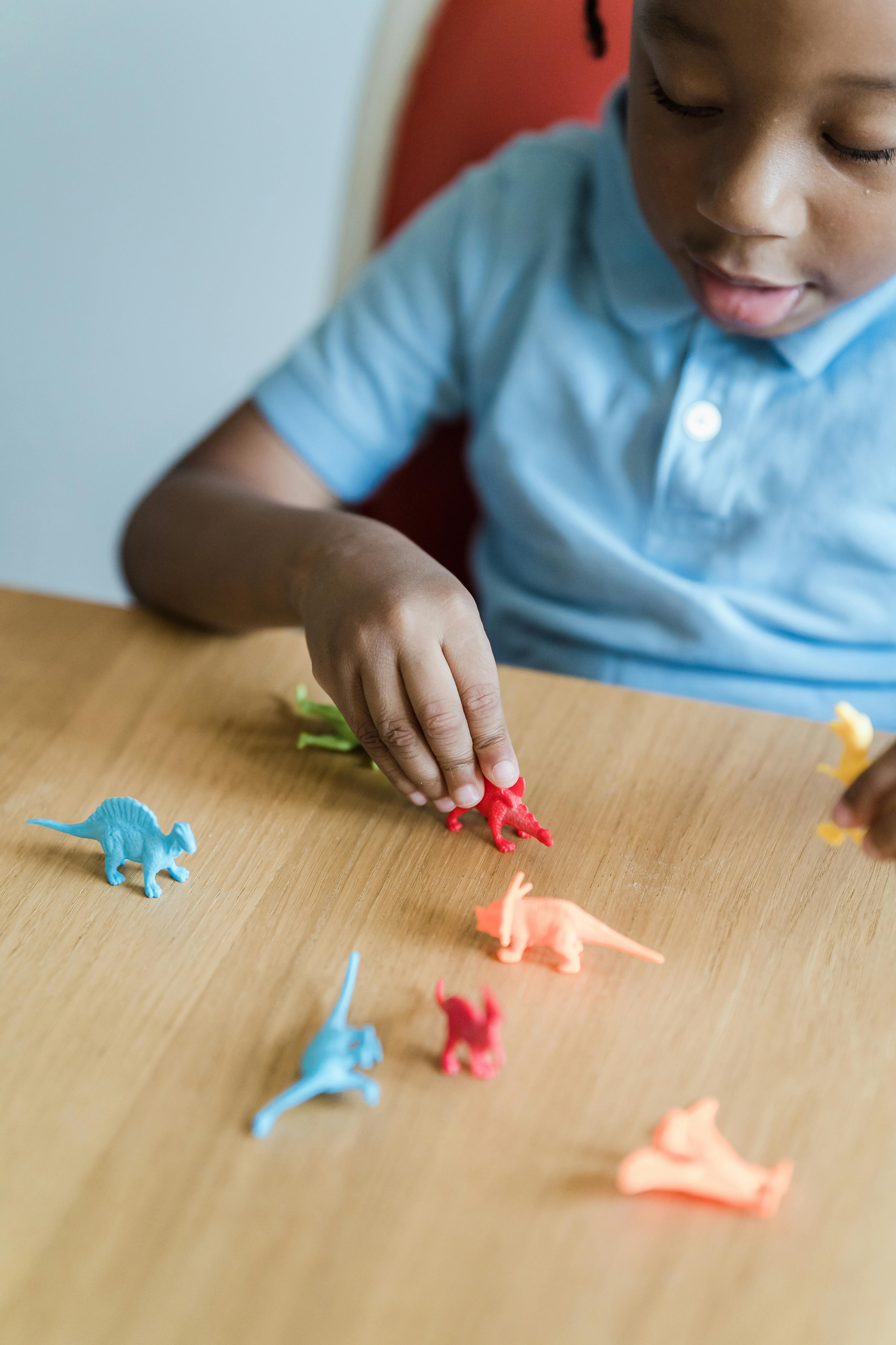 girl playing with plastic dinosaurs