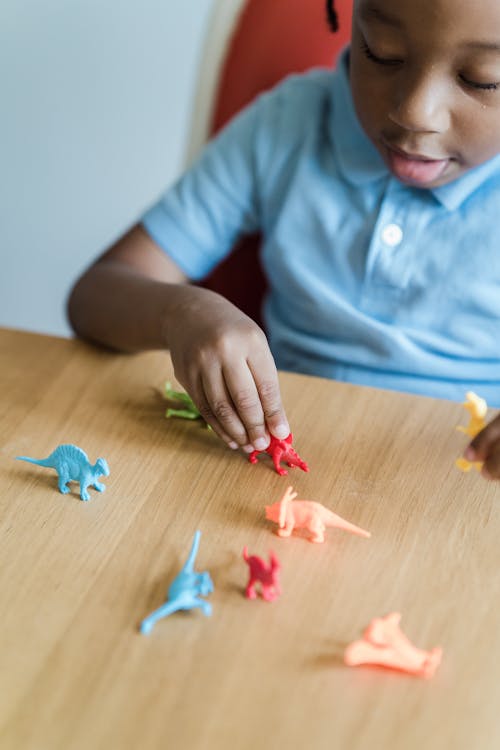 Free Girl Playing with Plastic Dinosaurs Stock Photo
