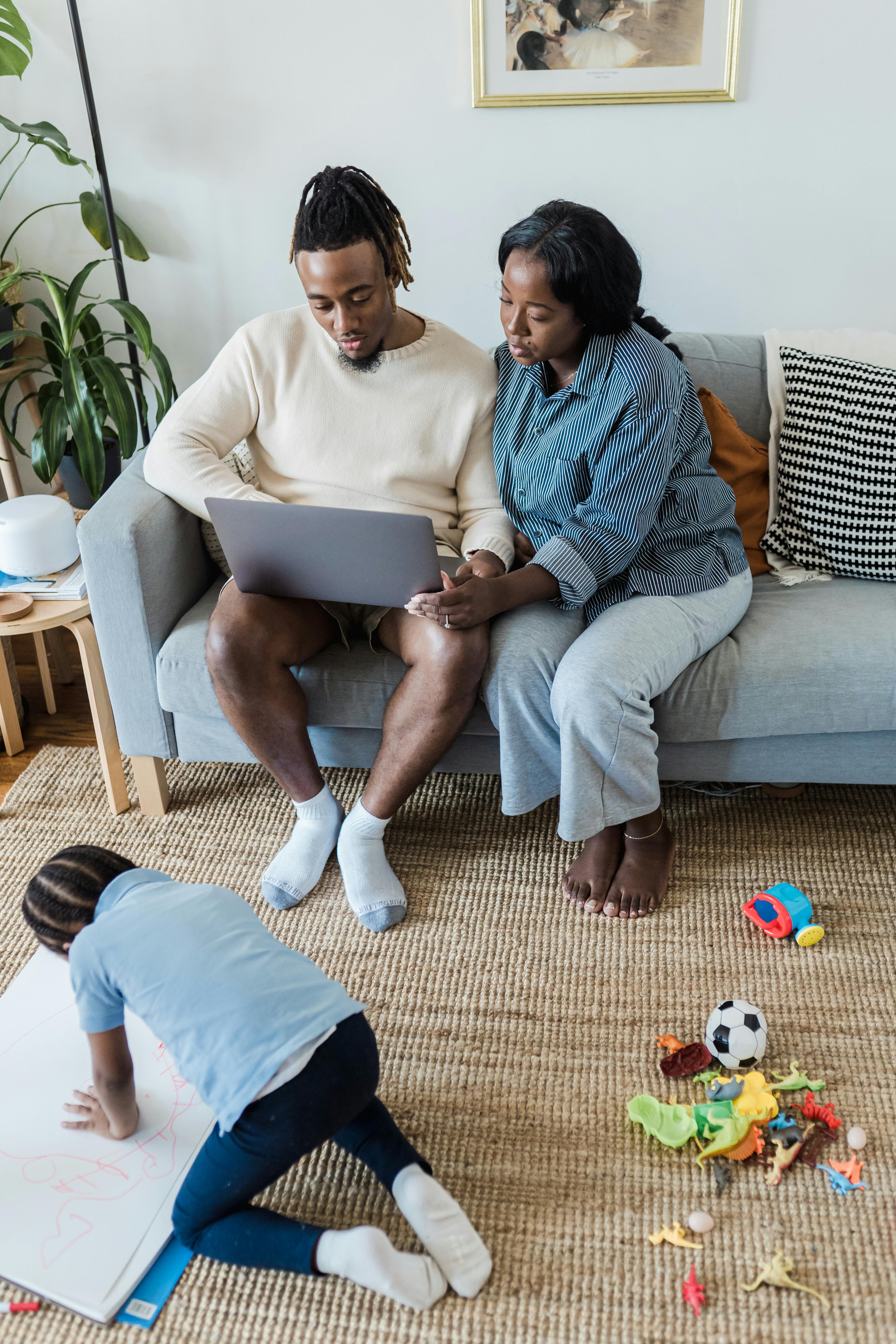 boy drawing and parents using laptop in a living room