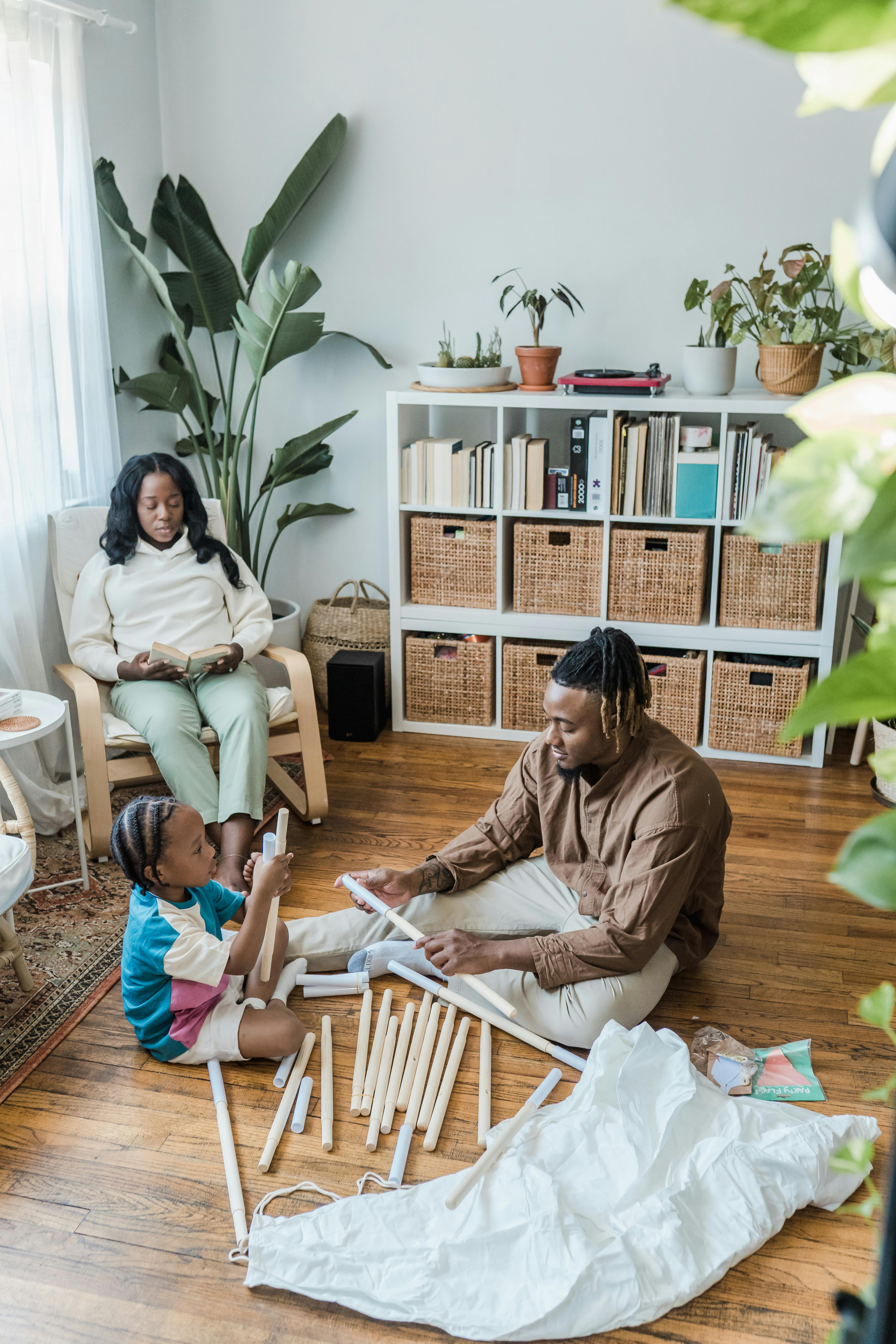 father and son building a toy teepee mother reading a book