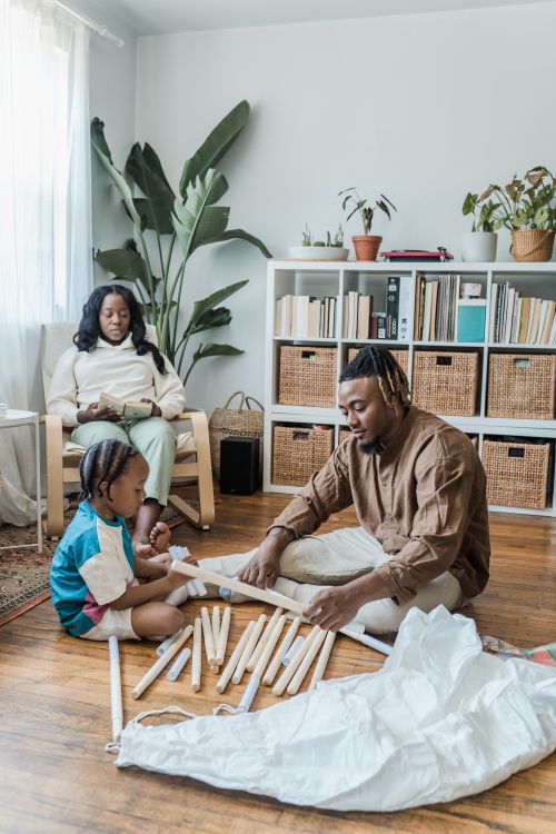 Free Mother, father, and child building a teepee indoors, enjoying family time in a cozy living room. Stock Photo