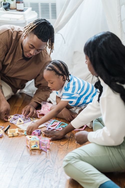 Free A joyful family spending quality time playing with colorful blocks on a wooden floor indoors. Stock Photo