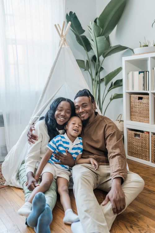 Free A joyful family of three embracing in a cozy and bright living room. Stock Photo