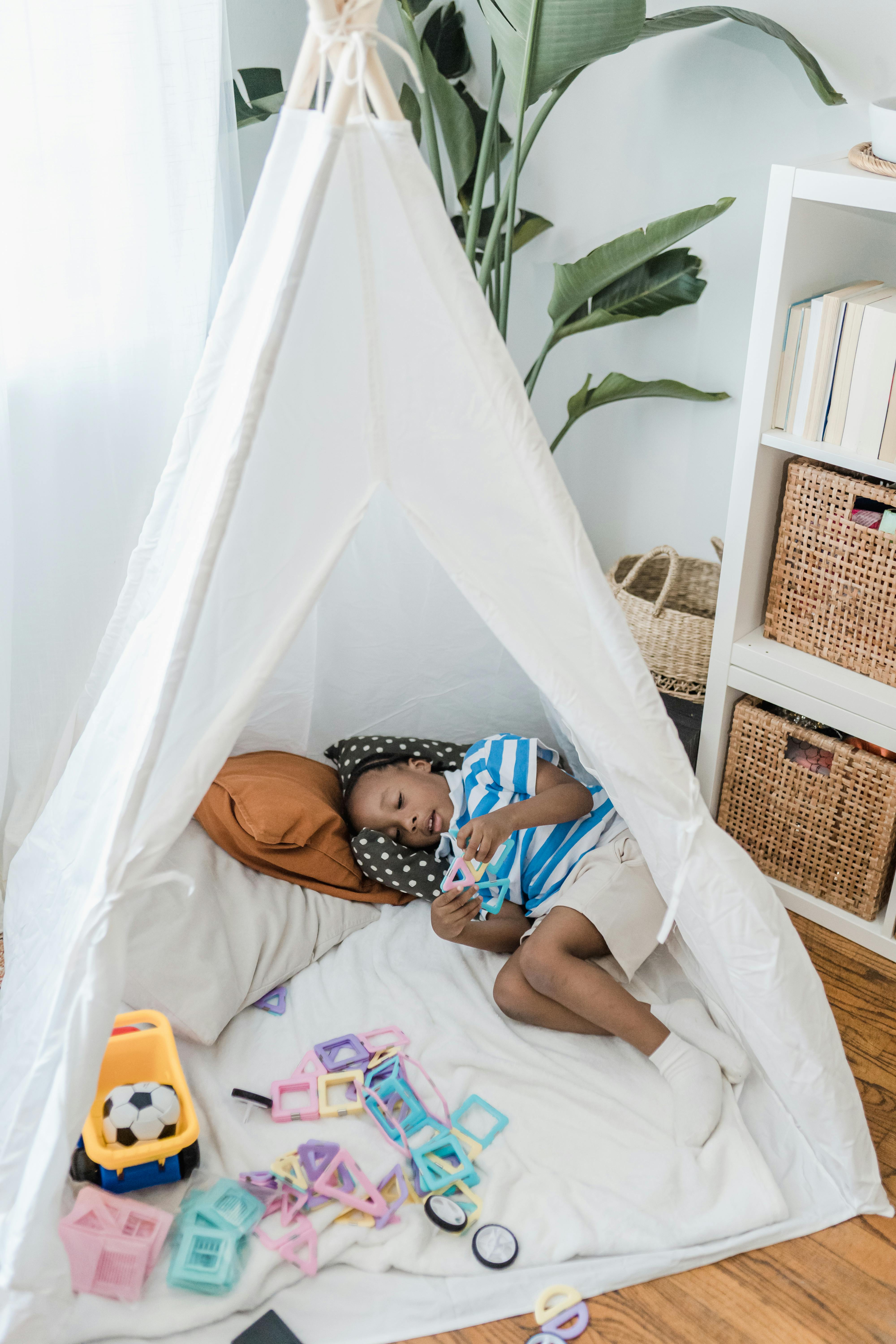 boy resting in a toy teepee