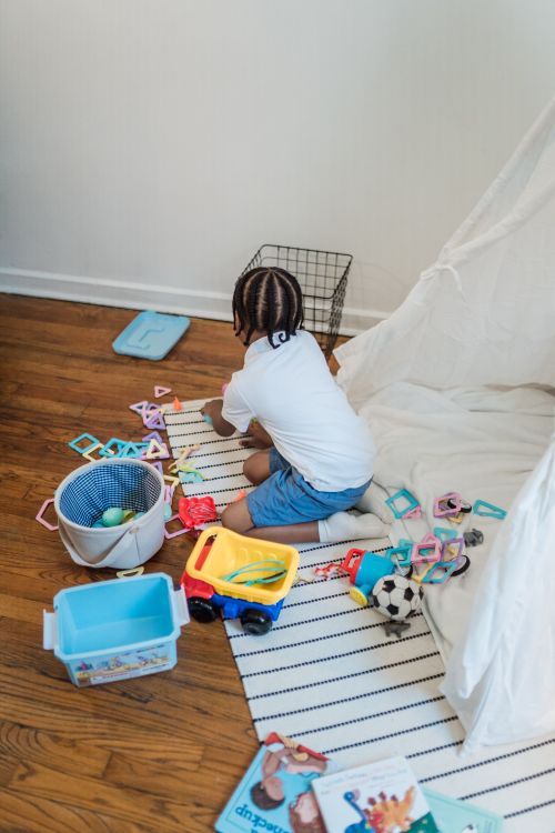 Free Young child playing with colorful toys indoors near a teepee tent. Stock Photo