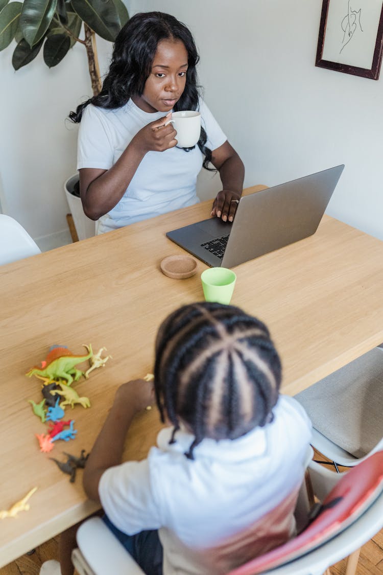 Little Girl Playing With Dinosaurs While Mother Works