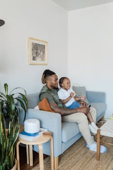 Father and daughter sitting on couch, enjoying family time in a cozy living room.