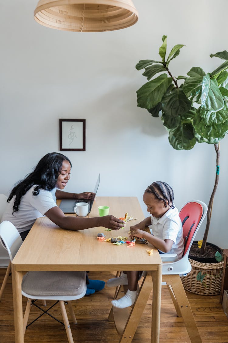 Mother Playing With Small Child At Kitchen Table