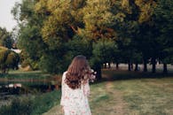 一位穿着花裙的女人沿着公园湖边的小路散步