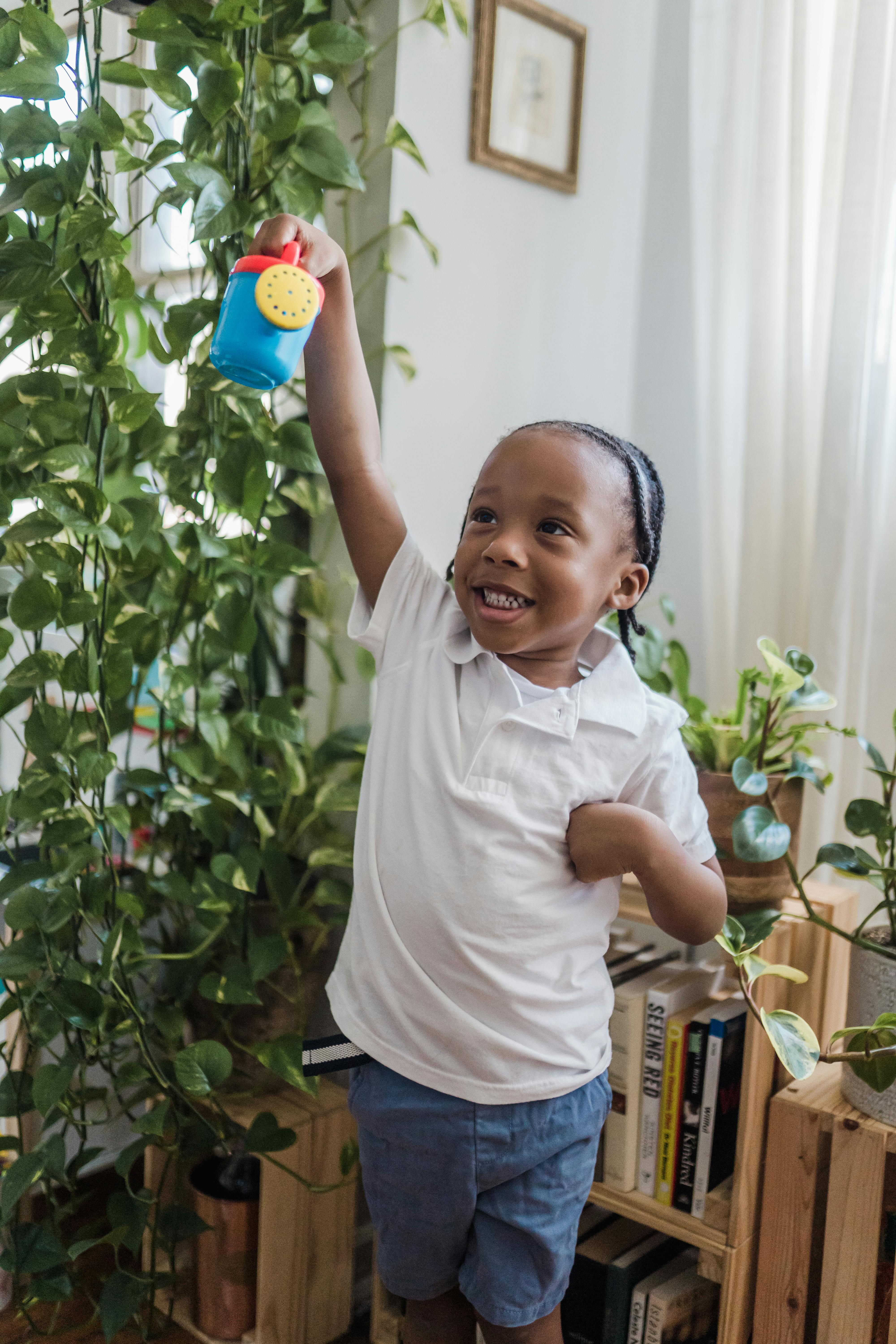 happy small boy playing with toy watering can