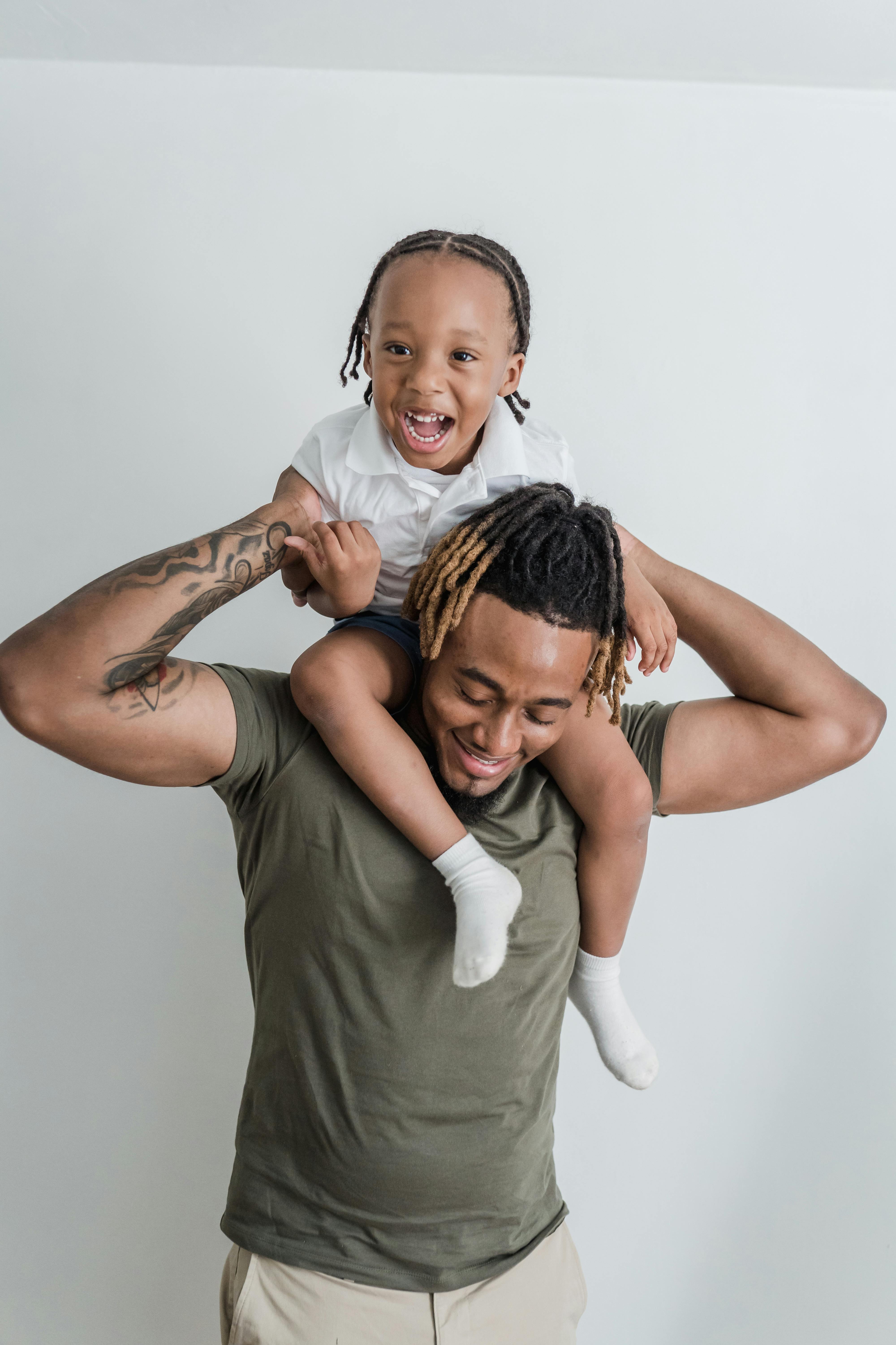 Father and son share a playful moment indoors with smiles and laughter.