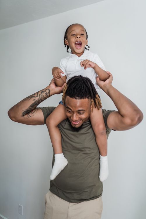 Free Father giving daughter a piggyback ride, sharing a joyful moment together indoors. Stock Photo