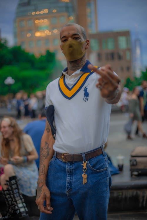 Man in a Face Mask Standing and Making an Obscene Gesture 