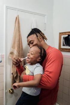 A joyful moment between father and daughter as they brush teeth together in the bathroom.