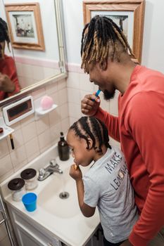 A father and son sharing bonding time while brushing teeth together.