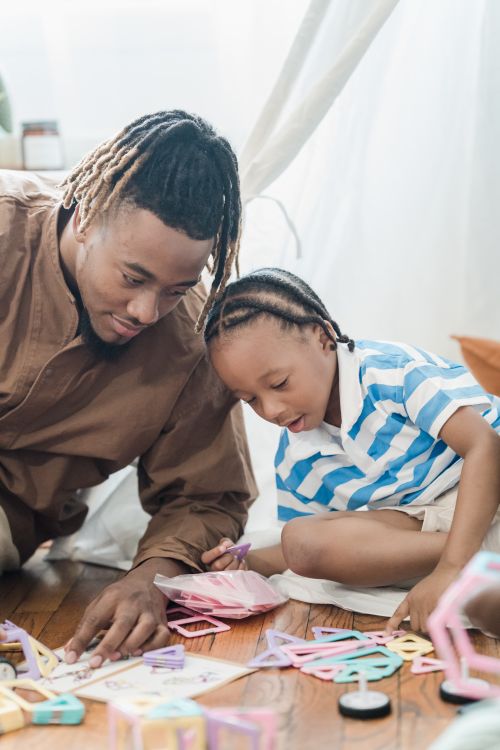 Free A father and his young son bonding and playing with toys at home, creating joyful memories. Stock Photo