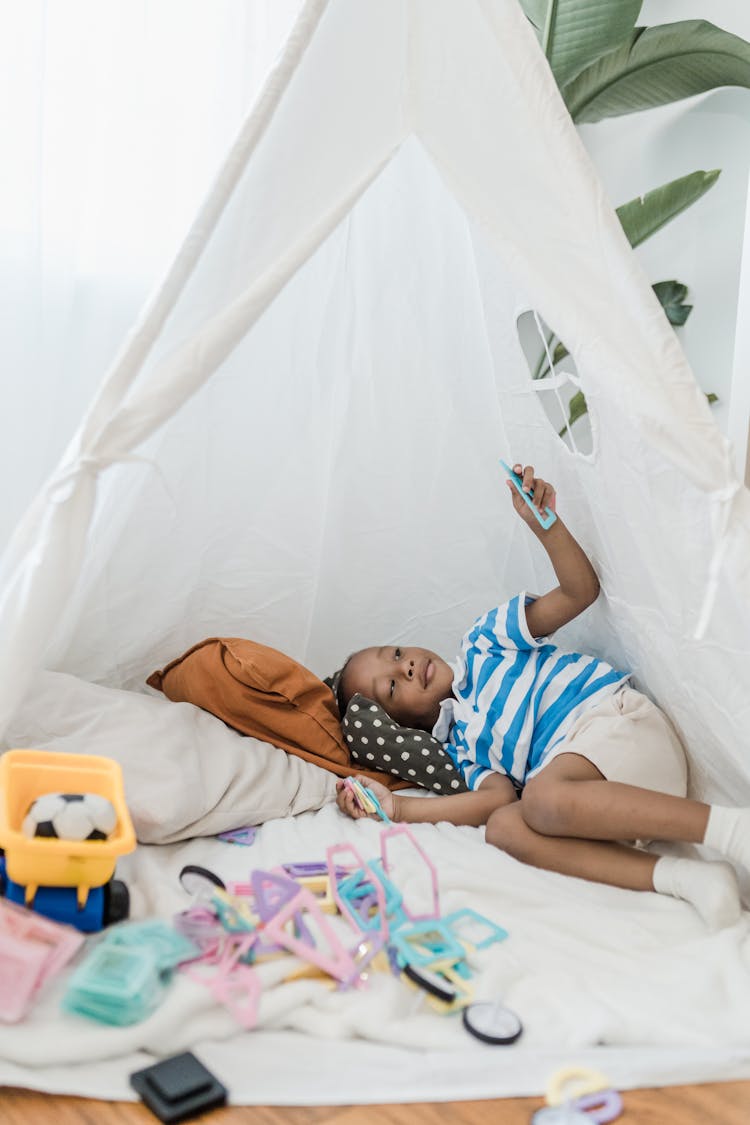 Little Girl Lying In Yurt With Toys