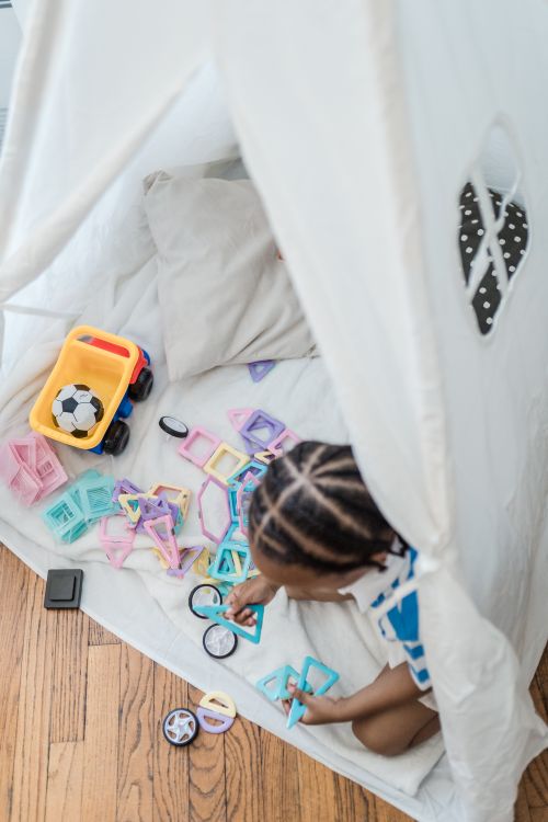 Free Child enjoying playtime with various toys inside an indoor play tent. Stock Photo