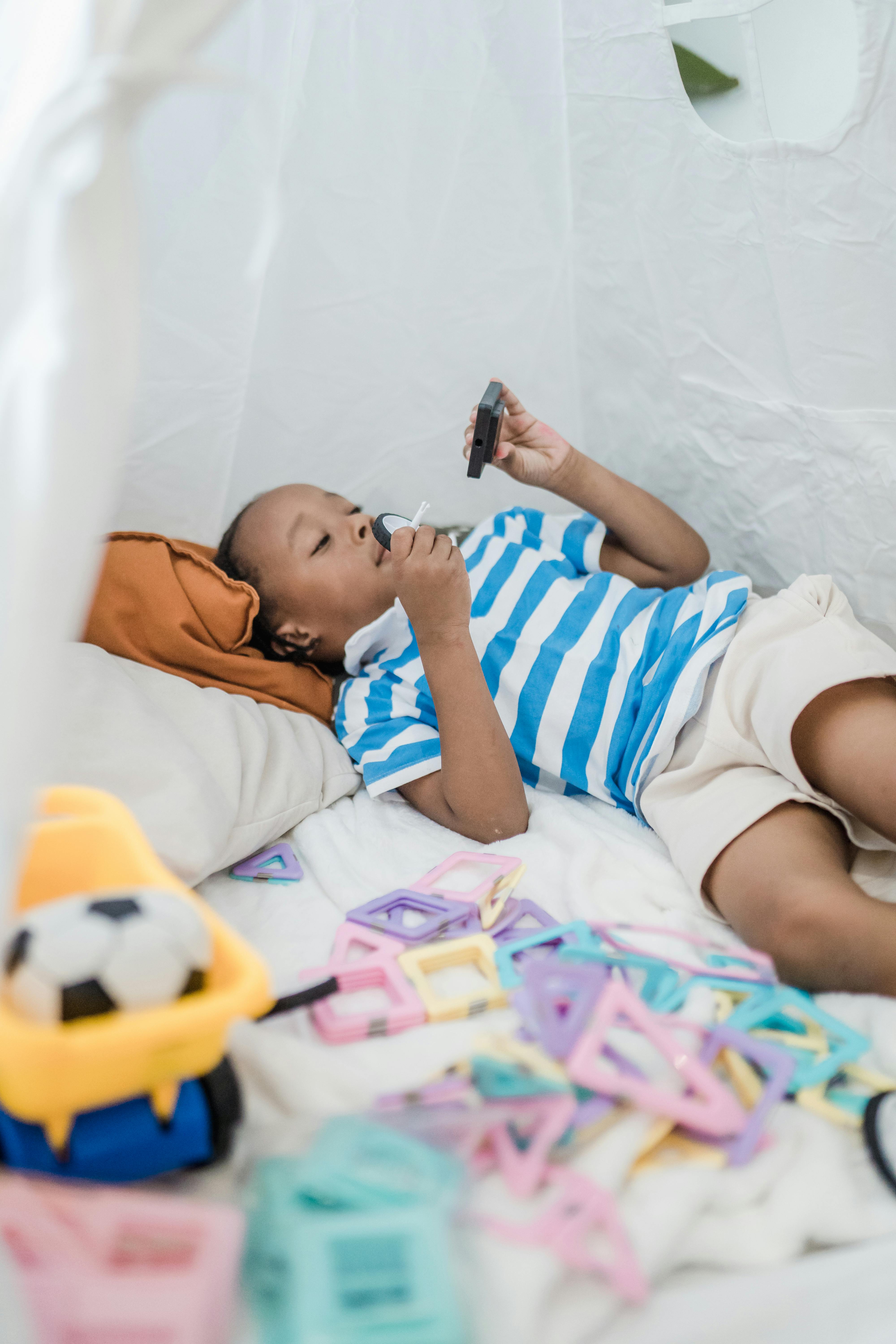 child lying on the bed and playing with toys