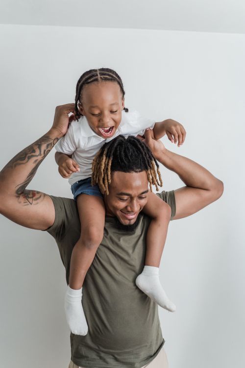 Free Happy father giving his daughter a piggyback ride indoors, sharing joyful moments. Stock Photo