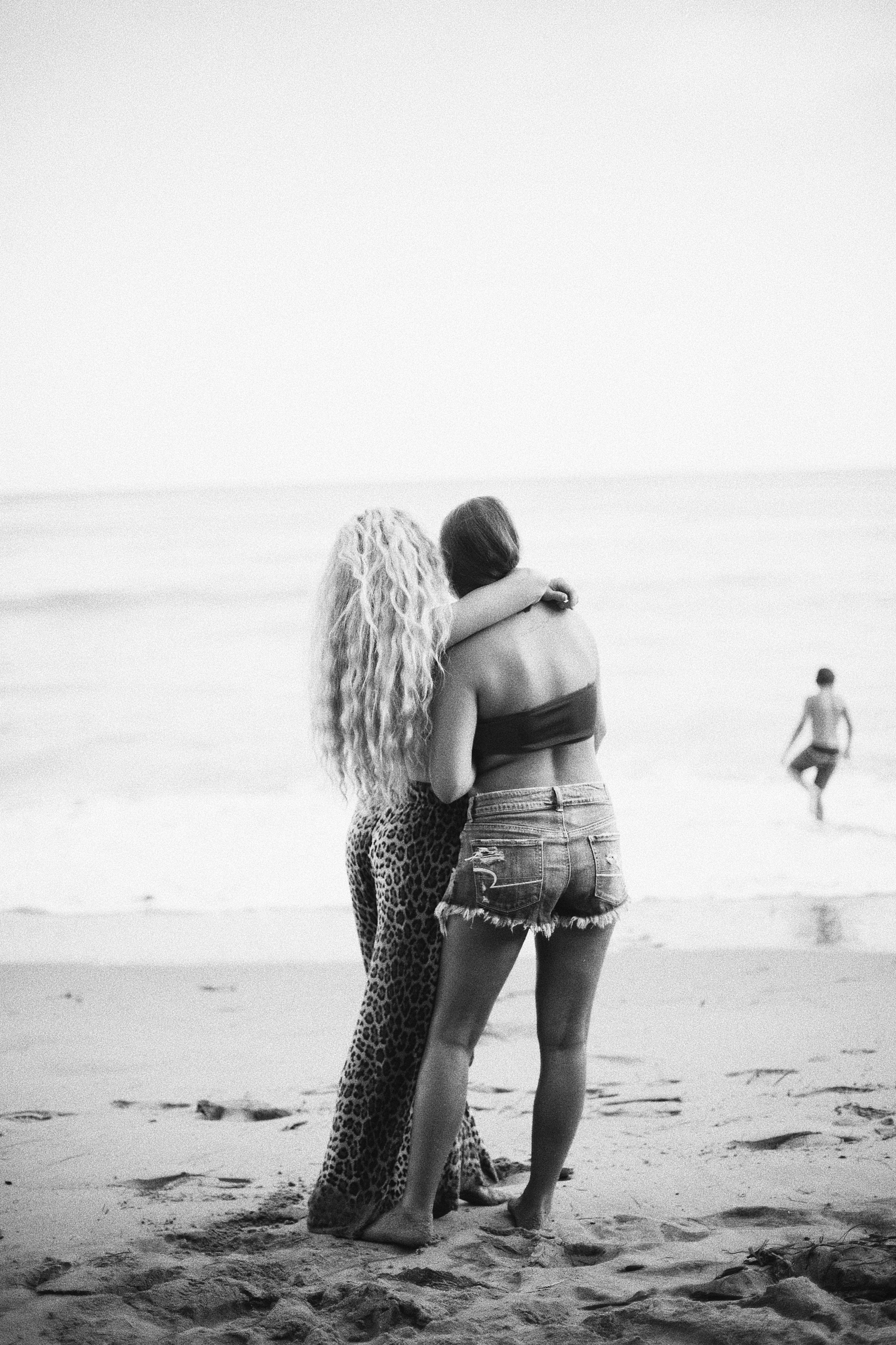 Captivating black and white image of two women embracing on a serene beach.